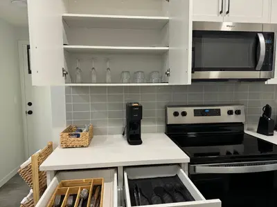 a kitchen with white cabinets and a stove top oven at Chic & Cozy 2-BR Suite at Glacier Ridge NW Calgary in Calgary