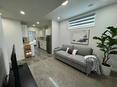 a living room with a couch and a television at Chic & Cozy 2-BR Suite at Glacier Ridge NW Calgary in Calgary