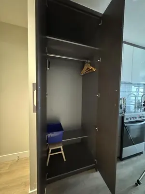 a black cabinet with a blue chair in a kitchen at Stylish Modern Apartment In The Heart Of Old Town Victoria in Victoria