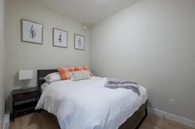 a bedroom with a bed with white sheets and orange pillows at Stylish Modern Apartment In The Heart Of Old Town Victoria in Victoria