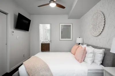 a bedroom with a white bed with pink pillows at Chic And Cozy Apartment In Old Town in Victoria