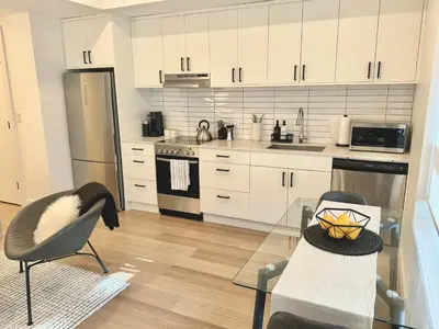 a kitchen with white cabinets and a glass table at Central Moodyville Retreat in North Vancouver