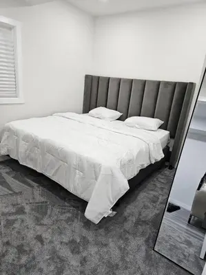 a bedroom with a large bed with white sheets at Comfort Guest Suite NE Calgary - Near Airport in Calgary