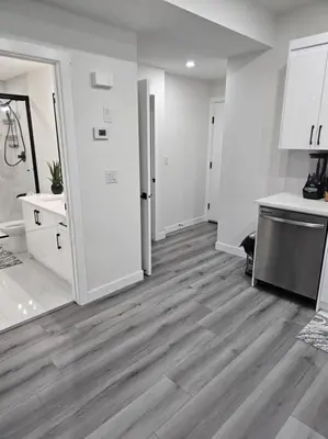 a kitchen with white walls and a wooden floor at Comfort Guest Suite NE Calgary - Near Airport in Calgary