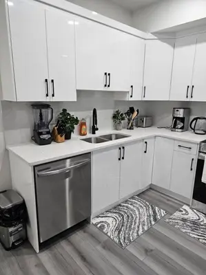 a kitchen with white cabinets and a sink at Comfort Guest Suite NE Calgary - Near Airport in Calgary