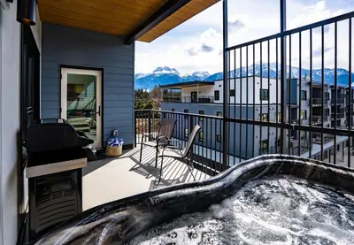 a hot tub on a balcony with a view of mountains at Mountain Revelation by Revelstoke Vacations in Revelstoke
