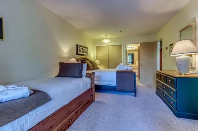 a bedroom with two beds and a desk with a lamp at Greystone Lodge 214 Ski-in Out in Whistler