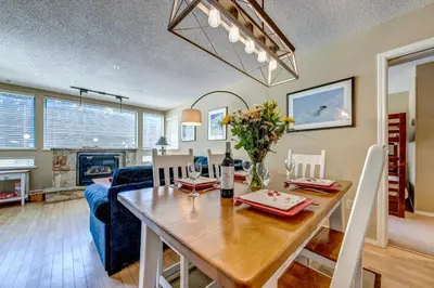 a dining room and living room with a wooden table at Greystone Lodge 202 Ski-in Out in Whistler