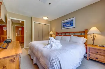 a bedroom with a large white bed and a desk at Greystone Lodge 202 Ski-in Out in Whistler