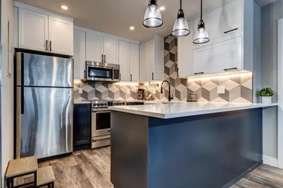 a kitchen with white cabinets and a stainless steel refrigerator at Greystone Lodge 329 Ski-in Out in Whistler