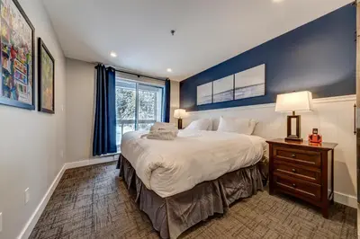 a bedroom with a large bed with a blue wall at Greystone Lodge 329 Ski-in Out in Whistler