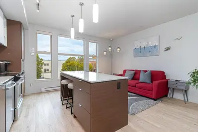 a kitchen and living room with a red couch at Chic And Cozy Condo In Old Town Victoria in Victoria