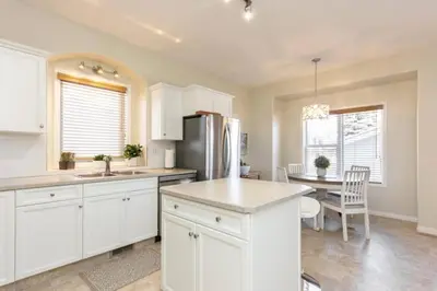 a kitchen with white cabinets and a table with a refrigerator at Spacious 3bedrm for family or business travellers in Red Deer