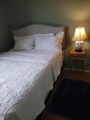 a bed with a white comforter and a table with a lamp at Elegant 4-Bedroom Family Home Master in Calgary