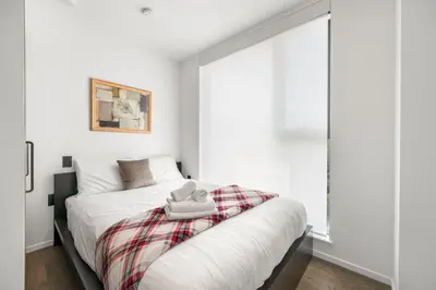 a bedroom with a bed with a plaid blanket on it at Luxury High-Rise Condo with Stunning Views in Vancouver
