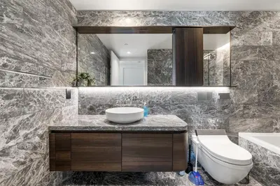 a bathroom with a sink and a toilet and a mirror at Luxury High-Rise Condo with Stunning Views in Vancouver