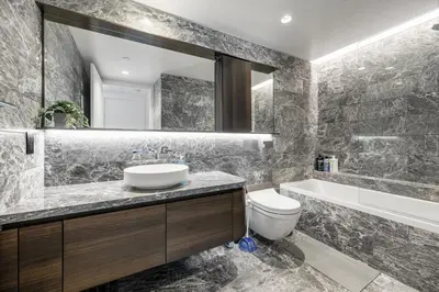a bathroom with a sink and a toilet and a mirror at Luxury High-Rise Condo with Stunning Views in Vancouver