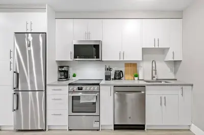 a kitchen with white cabinets and stainless steel appliances at Modern Studio Unit - Close to DT in Edmonton