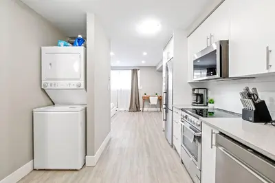 a white kitchen with a refrigerator and a stove at Modern Studio Unit - Close to DT in Edmonton