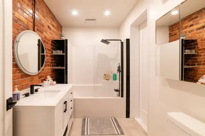 a bathroom with a white sink and a brick wall at Stylish downtown apartment in Grand Forks, BC in Grand Forks
