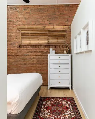 a bedroom with a brick wall and a bed and a dresser at Modern industrial suite in Grand Forks in Grand Forks