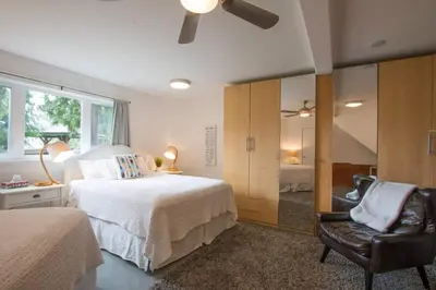 a bedroom with a bed and a chair and a mirror at Christina Lake Lakefront, Hot Tub, Amazing Views in Christina Lake