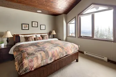 a bedroom with a large bed and a window at Dwight Out Chalet with Hot Tub in Big White