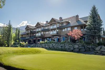 a large house on a golf course with a green at 2BR in Nicklaus North Clubhouse, Lake and Mountain Views, Gas Fireplace, Parking in Whistler