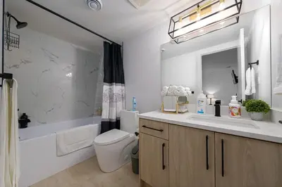a bathroom with a sink and a toilet and a tub at Modern Suite by Royal Alexandra Hospital l Free Parking WiFi Netflix in Edmonton