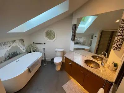 a bathroom with a tub and a toilet and a sink at Tyee Beach Oasis Bed and Breakfast in Nanoose Bay