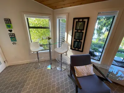a living room with chairs and a table and windows at Tyee Beach Oasis Bed and Breakfast in Nanoose Bay