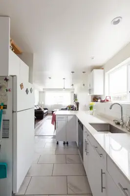 a kitchen with white cabinets and a white refrigerator at PNE Delight in Vancouver