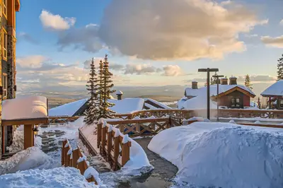 a snow covered yard with a house and a tree at Stonegate Resort Unit A205 in Big White