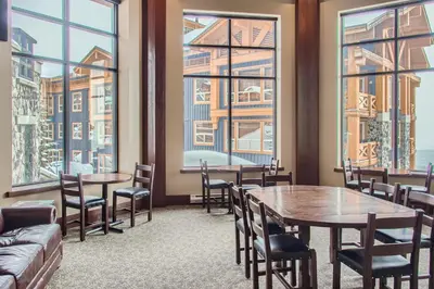 a restaurant with tables and chairs and large windows at Stonegate Resort Unit A205 in Big White