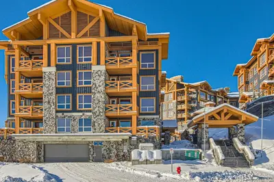 a large building in the snow with a ski lift at Stonegate Resort Unit B302 in Big White