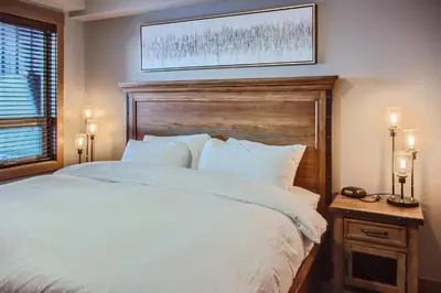 a bedroom with a large white bed with a wooden headboard at Stonegate Resort Unit B303 in Big White