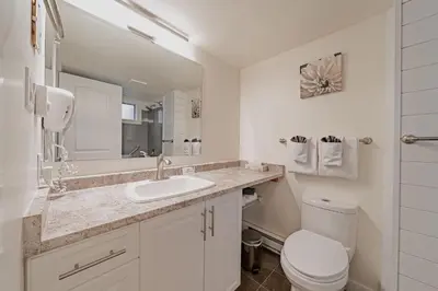 a bathroom with a sink and a toilet and a mirror at Shorewater Resort, Qualicum Beach in Qualicum Beach