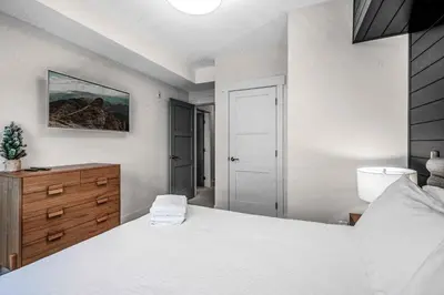 a bedroom with a white bed and a wooden dresser at Stonegate Resort Unit C106 in Big White