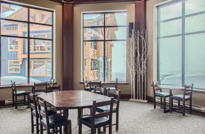 a dining room with a table and chairs and windows at Stonegate Resort Unit C103 in Big White