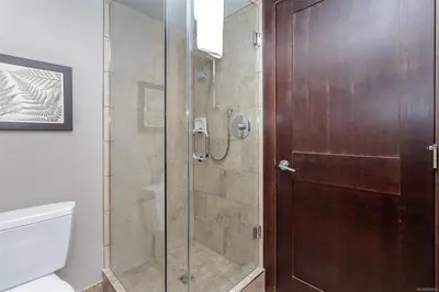 a shower with a glass door in a bathroom at Stylish Family Condo at Beachfront Resort in Parksville