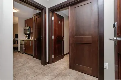 a hallway with wooden doors and a kitchen at Stylish Family Condo at Beachfront Resort in Parksville