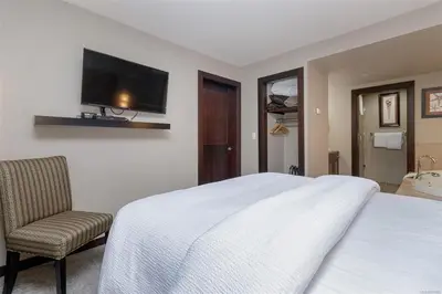 a bedroom with a bed and a chair and a television at Stylish Family Condo at Beachfront Resort in Parksville