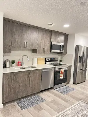 a kitchen with wooden cabinets and stainless steel appliances at Exquisite Basement Suite, 7mins away to Landmark Cinema and Malls in Calgary