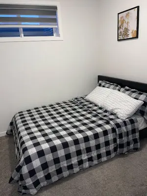 a bed with a black and white checkered blanket at Exquisite Basement Suite, 7mins away to Landmark Cinema and Malls in Calgary