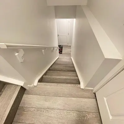 a staircase in a house with white walls and wooden floors at Exquisite Basement Suite, 7mins away to Landmark Cinema and Malls in Calgary