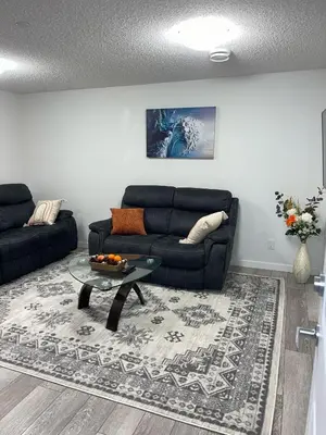 a living room with a black couch and a table at Exquisite Basement Suite, 7mins away to Landmark Cinema and Malls in Calgary