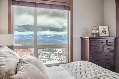a bedroom with a large window with a mountain view at Stonegate Resort Unit B401 in Big White