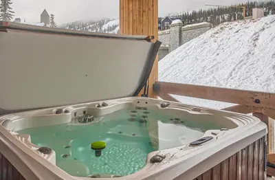 a hot tub on a balcony in the snow at Stonegate Resort Unit B204 in Big White