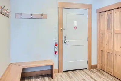 a hallway with a white door and a wooden bench at Stonegate Resort Unit B204 in Big White