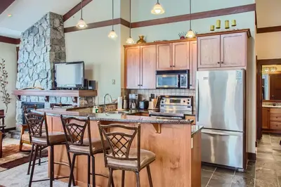 a kitchen with wooden cabinets and a island with bar stools at Stonegate Resort Unit A401 in Big White